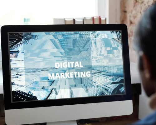 An individual focused on digital marketing on a desktop computer in a cozy workspace.